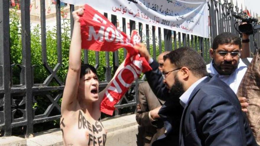 Un hombre intenta arrancar la pancarta a una de las tres activistas de Femen detenidas ayer en Túnez.  // Efe