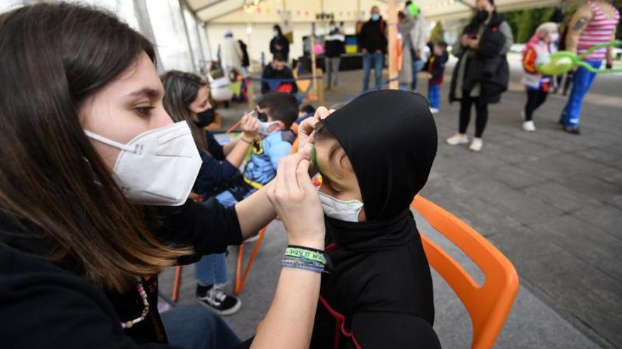 Una monitora maquilla a un niño en una fiesta de Entroido.