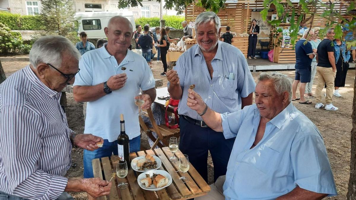 Asistentes a la fiesta, ayer, prueban raciones de lamprea seca con vino de Arbo.   | // D.P.