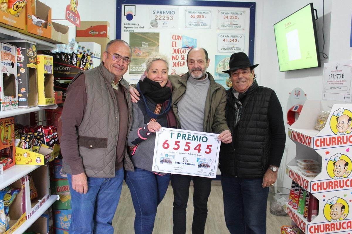 Félix Pérez, el dueño del estanco y punto de venta de loterías que ha dado el premio en El Carpio, junto a varios clientes y amigos, con el cartel del número premiado.