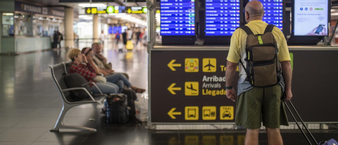 Un home mira un panell d’arribades i eixides a l’aeroport del Prat