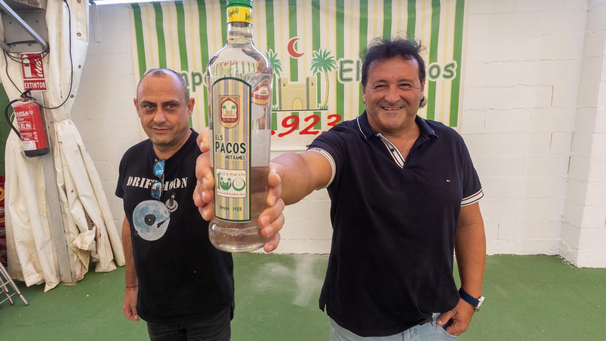 Pere y Manu, vicepresidente y presidente de Los Pacos con la botella de anís del centenario y su logo.