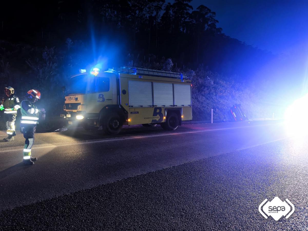 Un vehículo de los Bomberos de Castropol junto al vehículo volcado