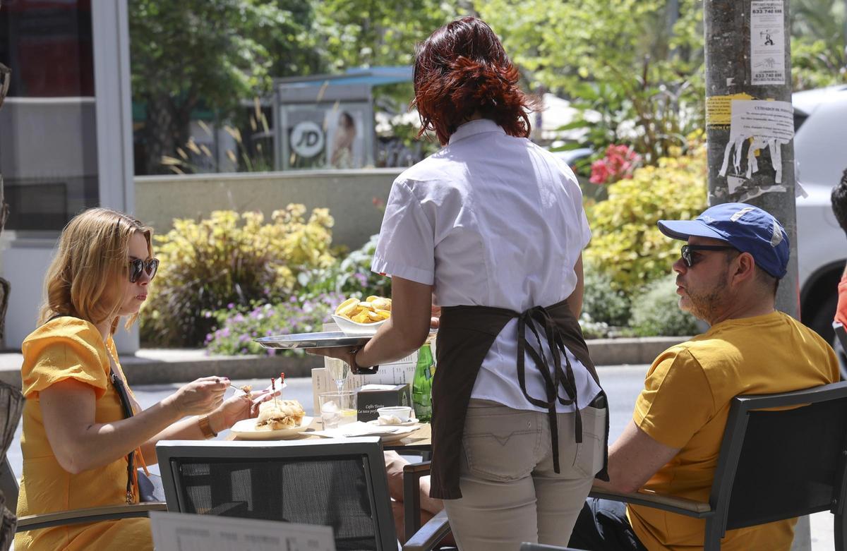 Una camarera atiende a los clientes de una terraza en Alicante.