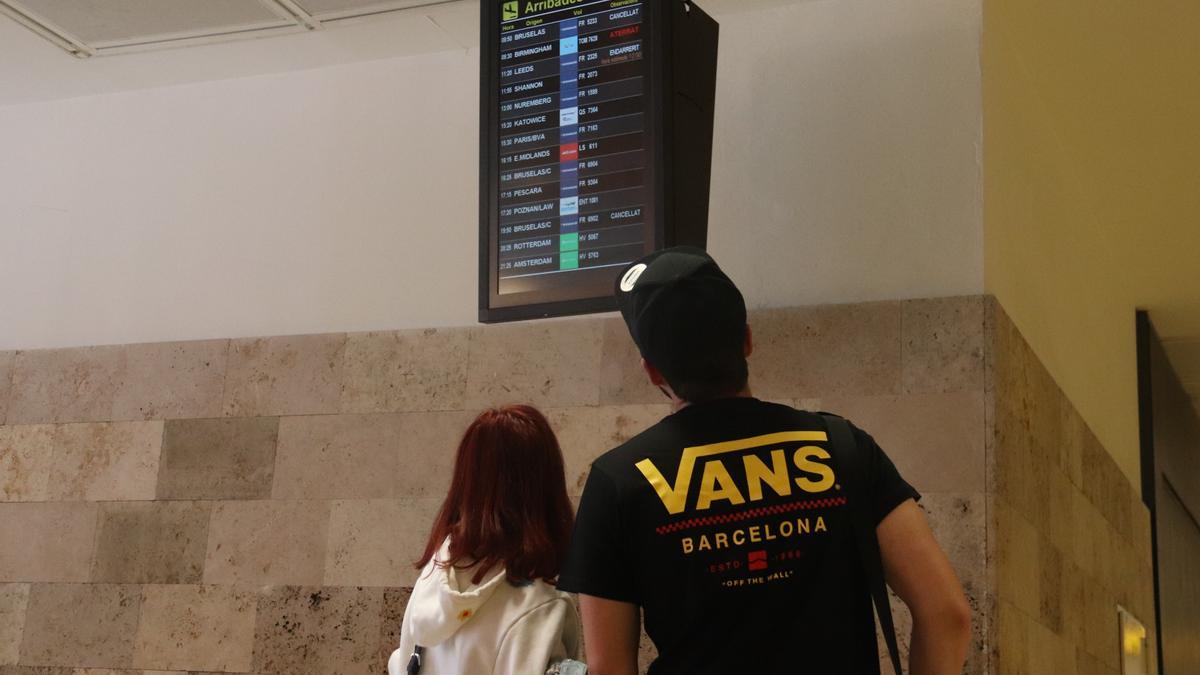 Dos passatgers consultant la pantalla d&#039;informació de l&#039;aeroport de Girona