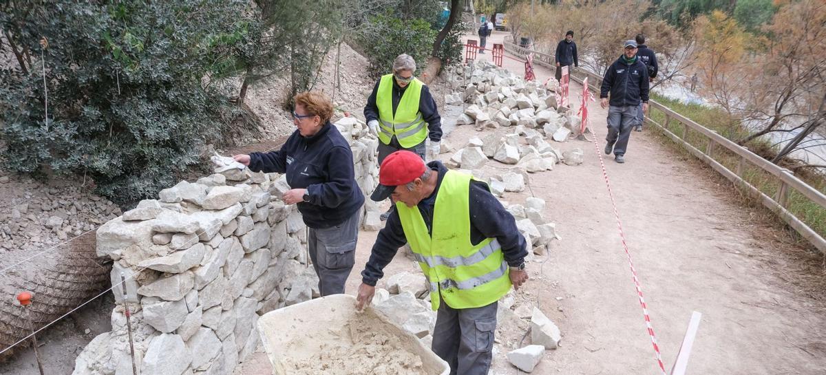 Integrantes del Taller de Empleo Elche XVII trabajando en la construcción de un muro al lado de la ladera del río Vinalopó de la ciudad. | ÁXEL ÁLVAREZ