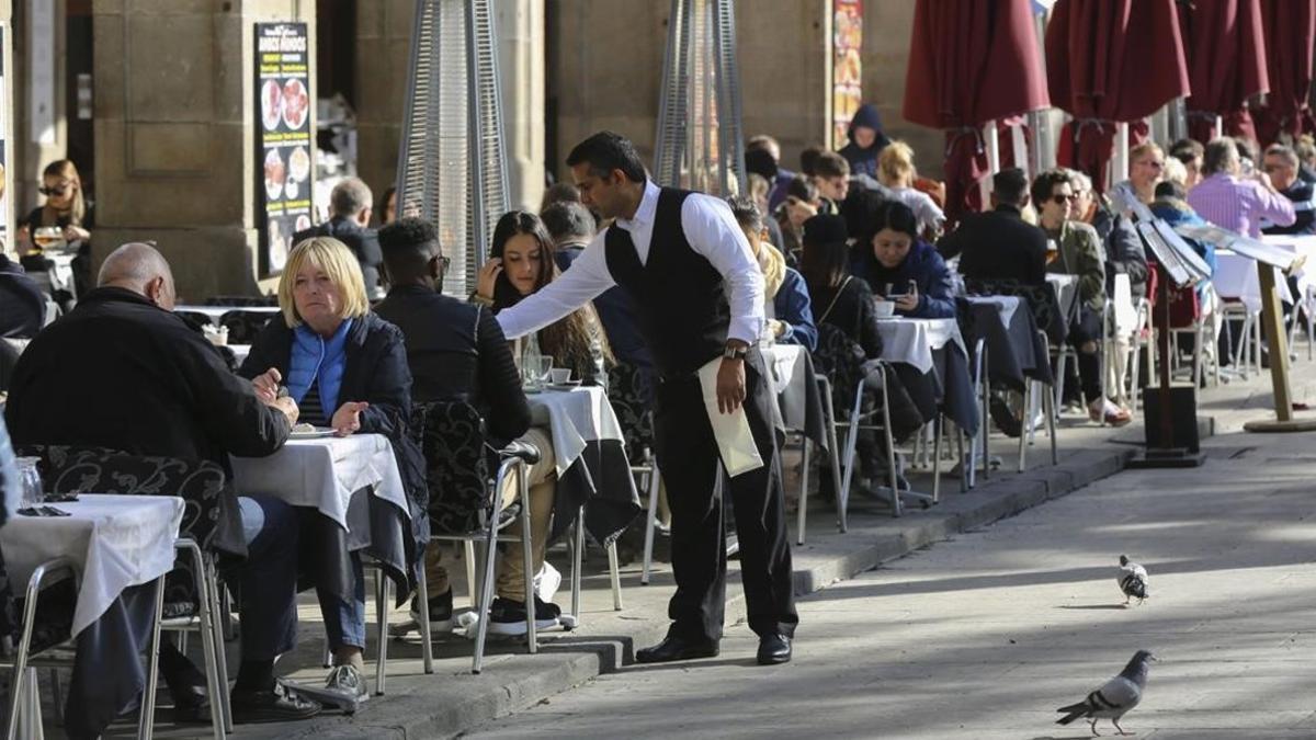 Un camarero sirve unas mesas en un restaurante de la plaza Reial de Barcelona