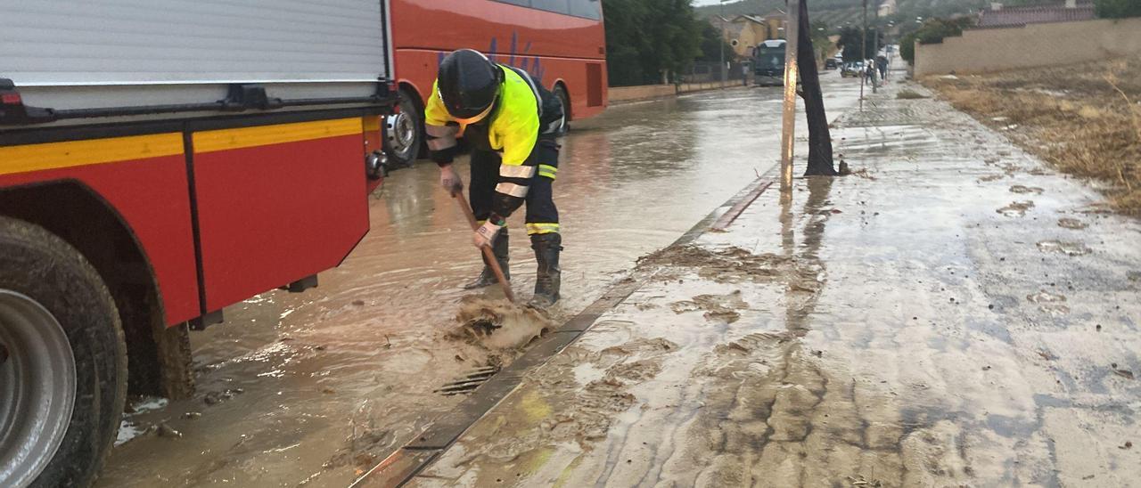 Un operario trabaja para desatascar una rejilla de evacuación de agua atorada por el lodo.