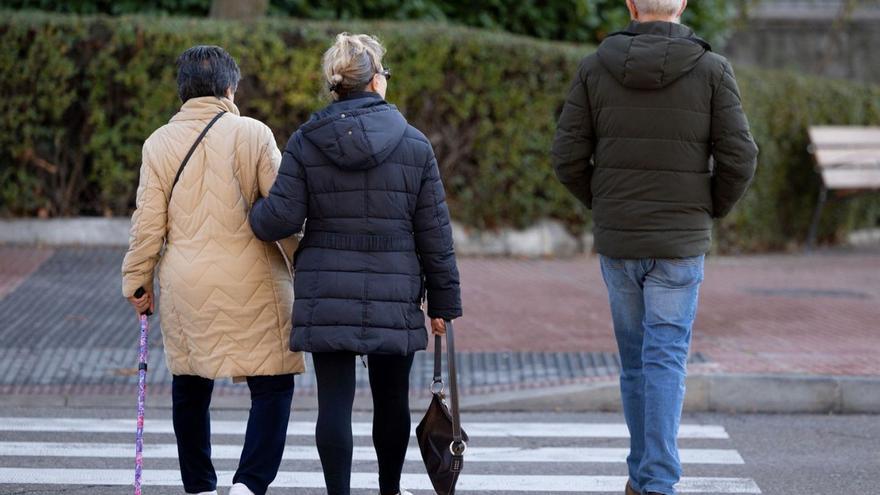 Una mujer con bastón cruza una calle ayudada por otra. | E. P.