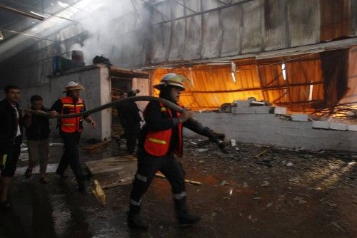 Firefighters try to extinguish a fire at a factory, which according to Palestinians was hit by an Israeli air strike in Gaza
