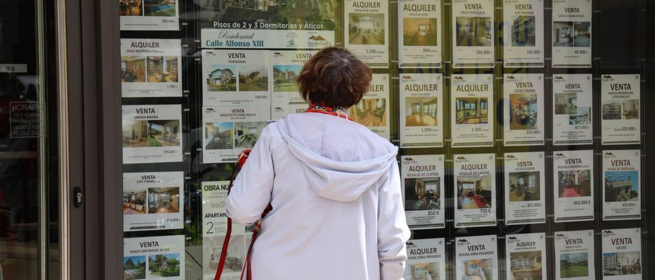 Una mujer observa los anuncios de ventas y alquileres en una inmobiliaria.