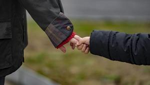 Un niño, agarrado de la mano de su madre