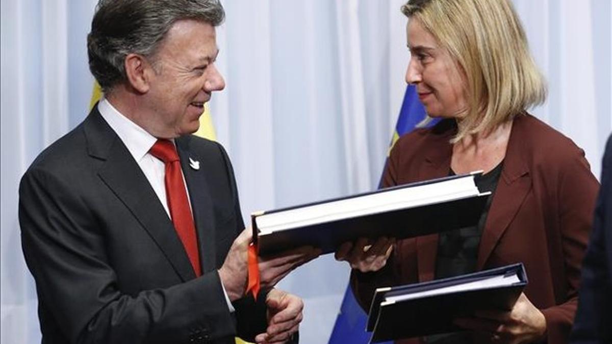 Santos y Mogherini intercambian los documentos, durante la ceremonia.