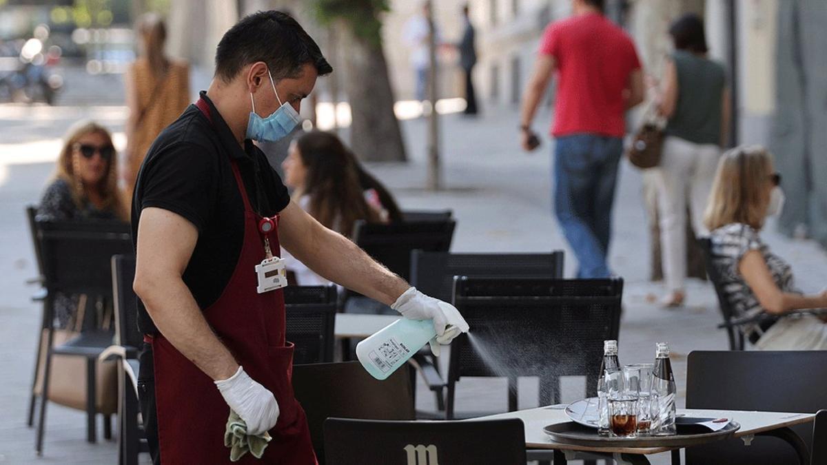 Un camarero desinfecta una mesa de una terraza de Madrid, el 29 de julio