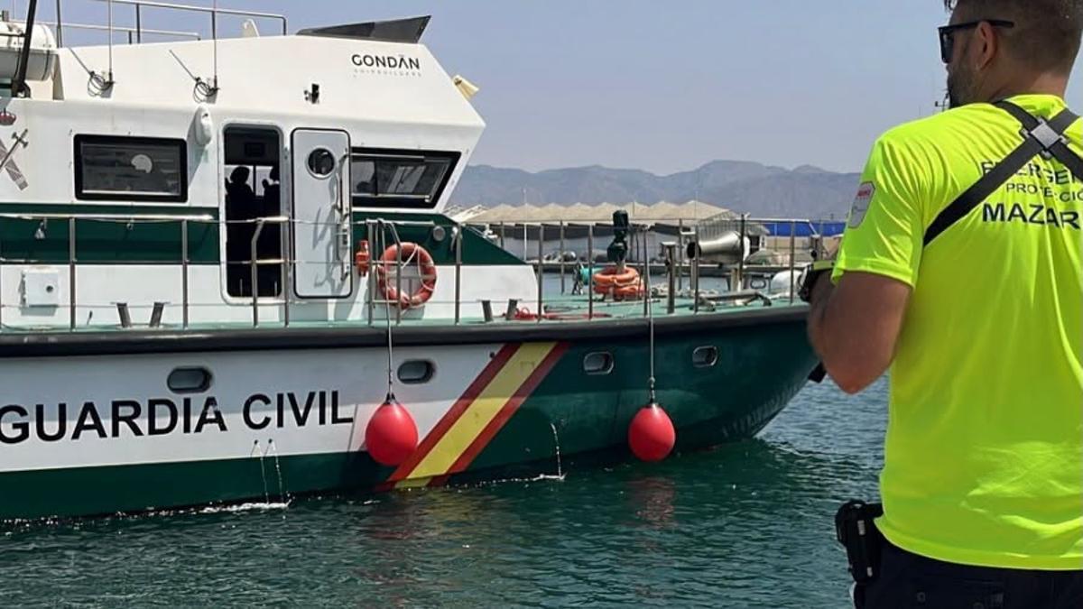 Un miembro de Protección Civil, junto al barco que trasladó a tierra el cuerpo.