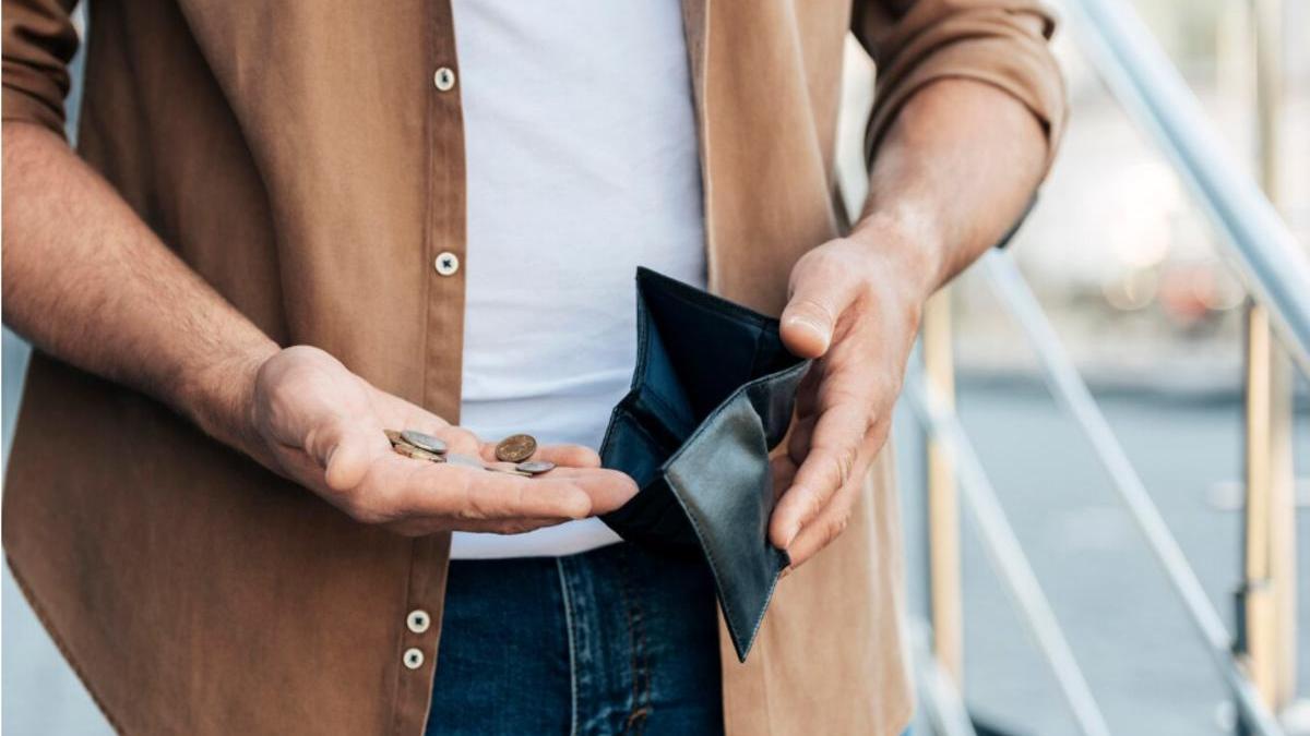 Un home consulta els diners que té a la seva cartera