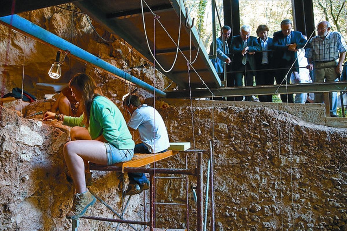 Arqueòlegs en una de les coves de Serinyà, ahir, durant la visita de les autoritats. Els estrats més profunds tenen 125.000 anys. (JOAN CASTRO / ICONNA)