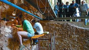 Arqueòlegs en una de les coves de Serinyà, ahir, durant la visita de les autoritats. Els estrats més profunds tenen 125.000 anys. (JOAN CASTRO / ICONNA)