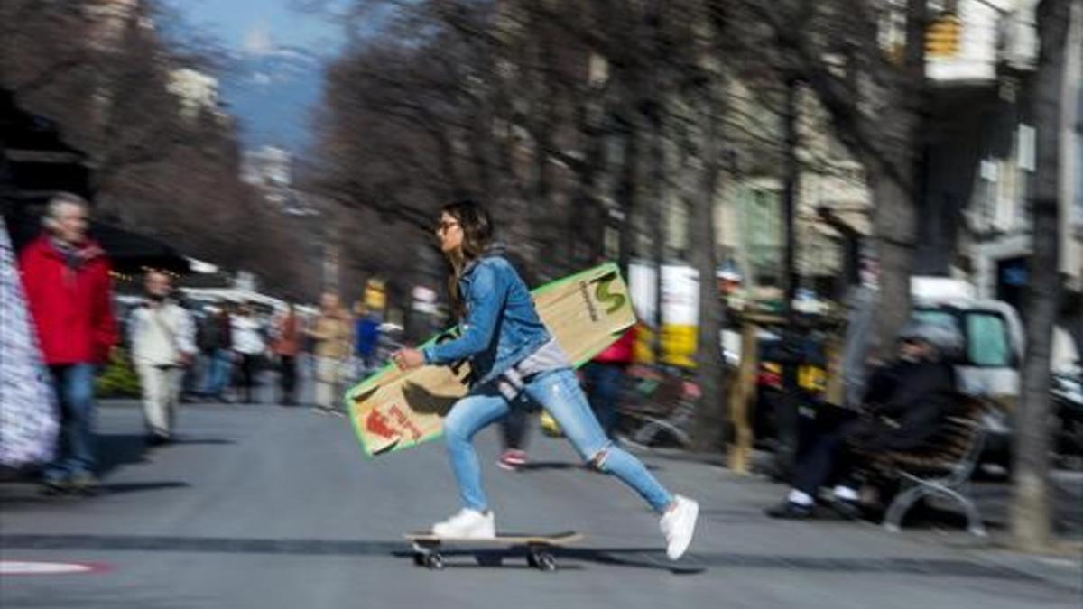 Gisela Pulido cruza la Rambla de Catalunya de Barcelona sobre un monopatín con su inseparable tabla.