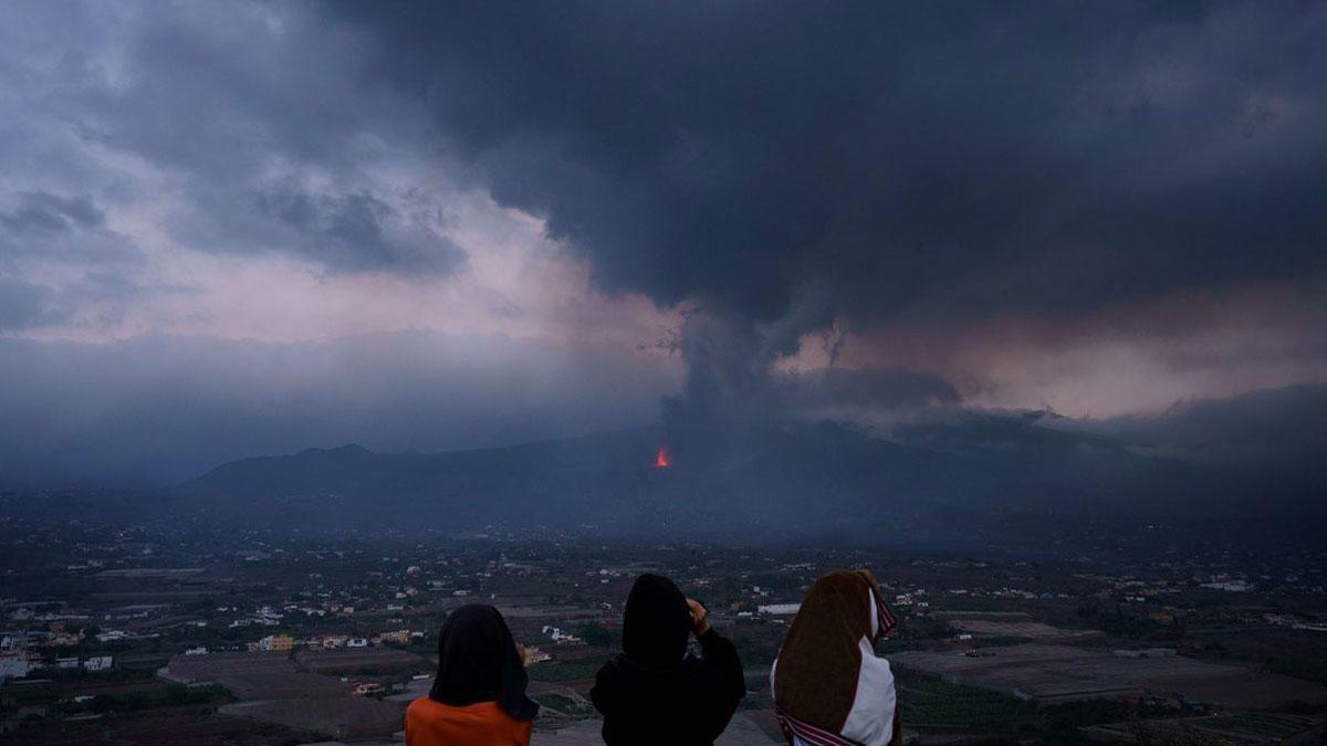 Unas niñas buscan con prismáticos su vivienda en el barrio de El Paraíso, una de las zonas más afectadas por la erupción que tiene lugar en la isla de La Palma. /