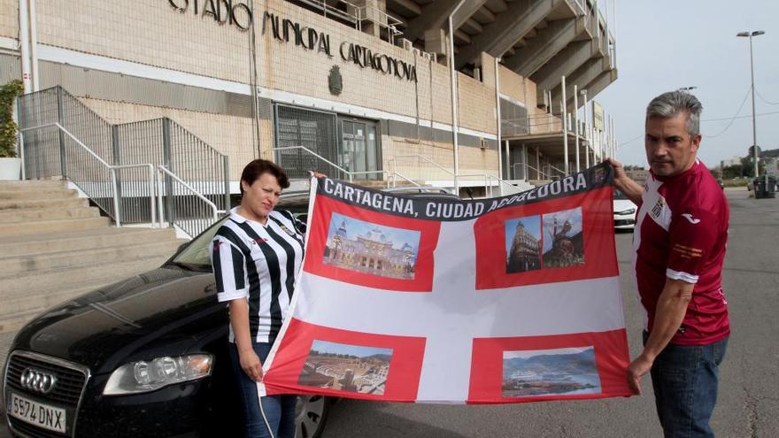 Gloria e Isi en la puerta del estadio, con la bandera a la que acuden a cada campo y con el vehículo con el que recorren miles de kilómetros.
