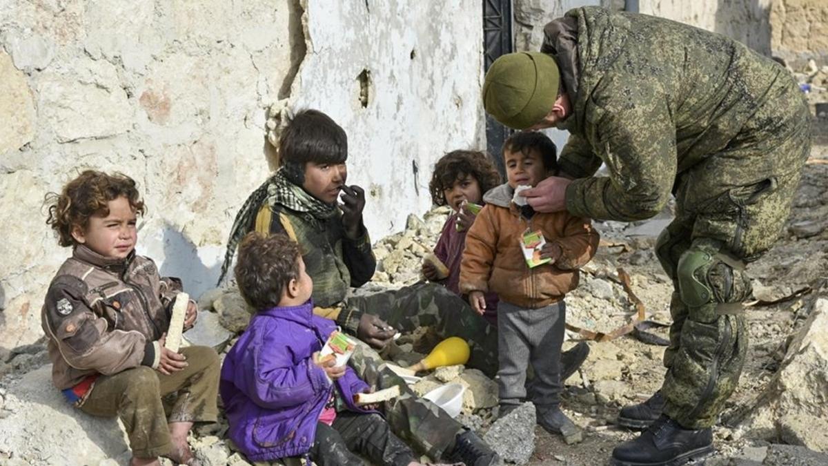 Un soldado ruso atiende a unos niños sirios en Aleppo, Siria.