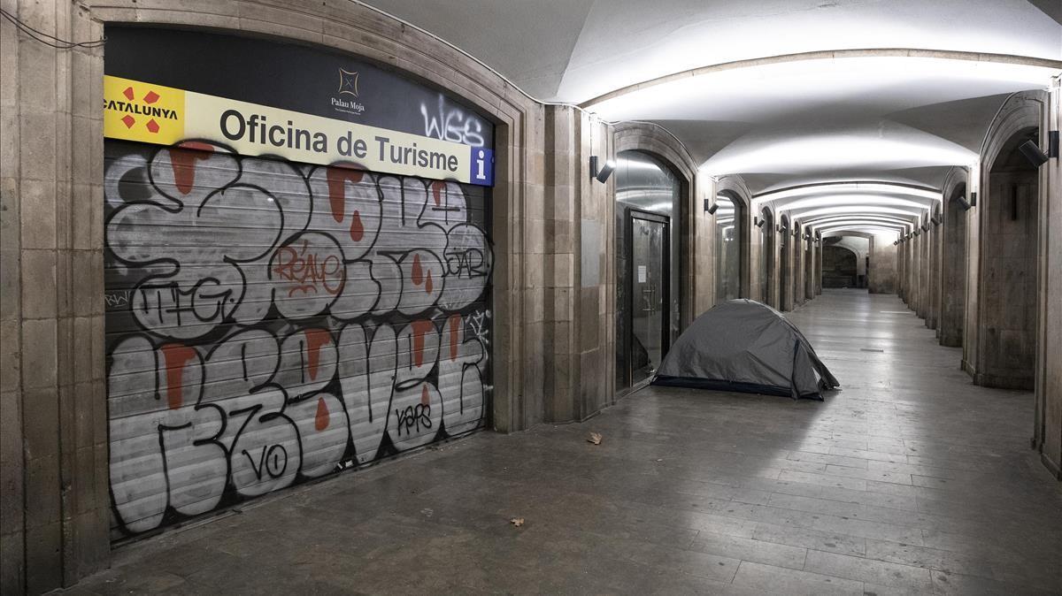 Un sintecho duerme en su tienda de acampada junto a la Oficina de Turismo de la Rambla.