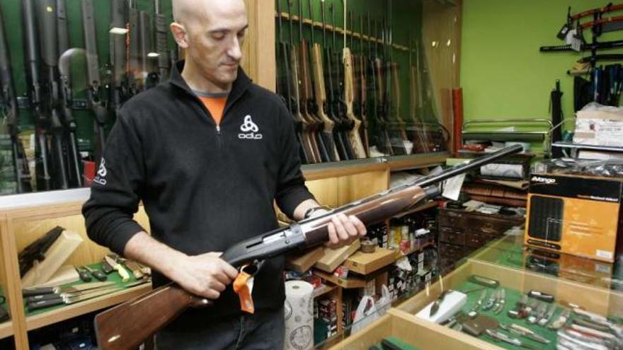 Antonio Toribio muestra una de las escopetas de caza que vende en su armería. / xoán álvarez