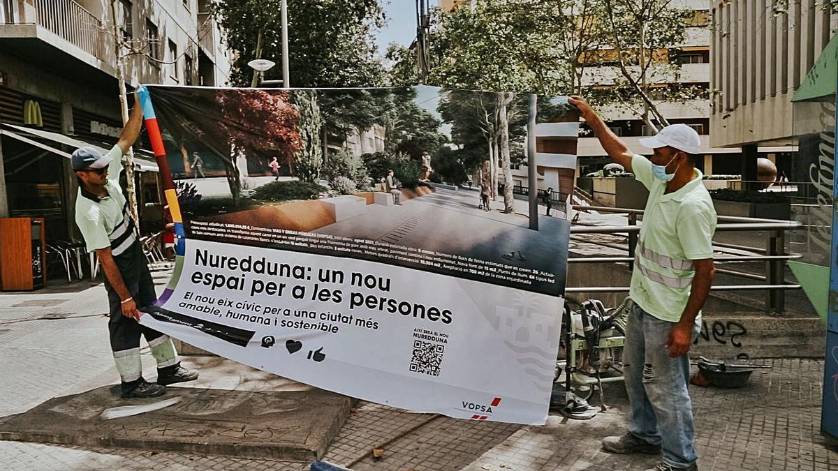 Dos operarios aguantan la gran pancarta que anuncia la peatonalización de la calle. | B. ARZAYUS