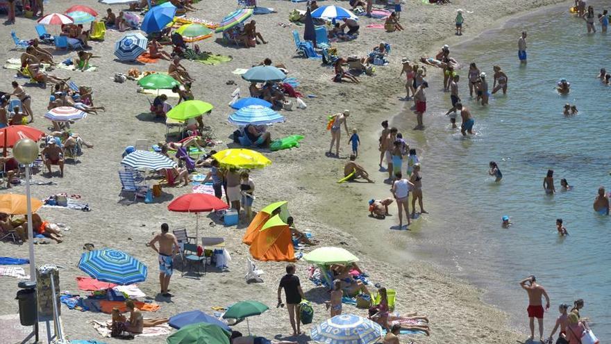 En Cartagena, la playa de Cala Cortina, en una imagen tomada ayer, se llena de bañistas que disfrutan del turismo de sol y playa en veran