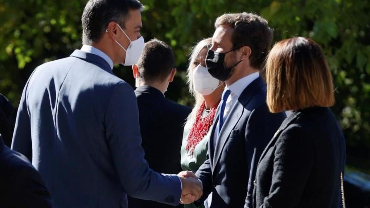 El presidente del Gobierno, Pedro Sánchez, saluda al líder del PP, Pablo Casado, a su llegada al monasterio de Yuste, en el que el rey Felipe VI entregó el Premio Europeo Carlos V a la todavía canciller alemana, Angela Merkel, el pasado 14 de octubre de 2021.