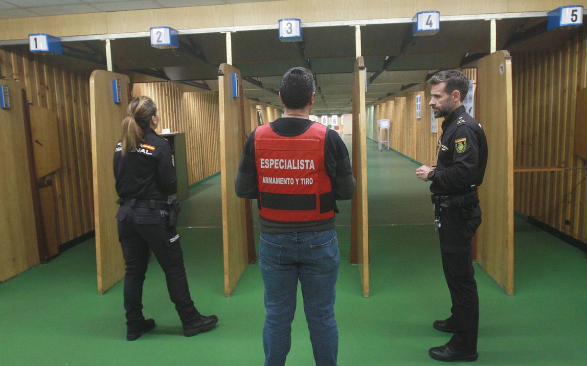 El instructor en la zona de tiro
de la Comisaría ourensana,
con dos agentes. | // I.O.
