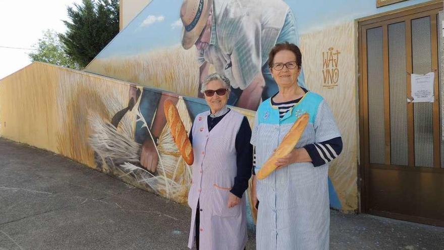 Dos vecinas posan junto a un mural que refleja una estampa agraria.