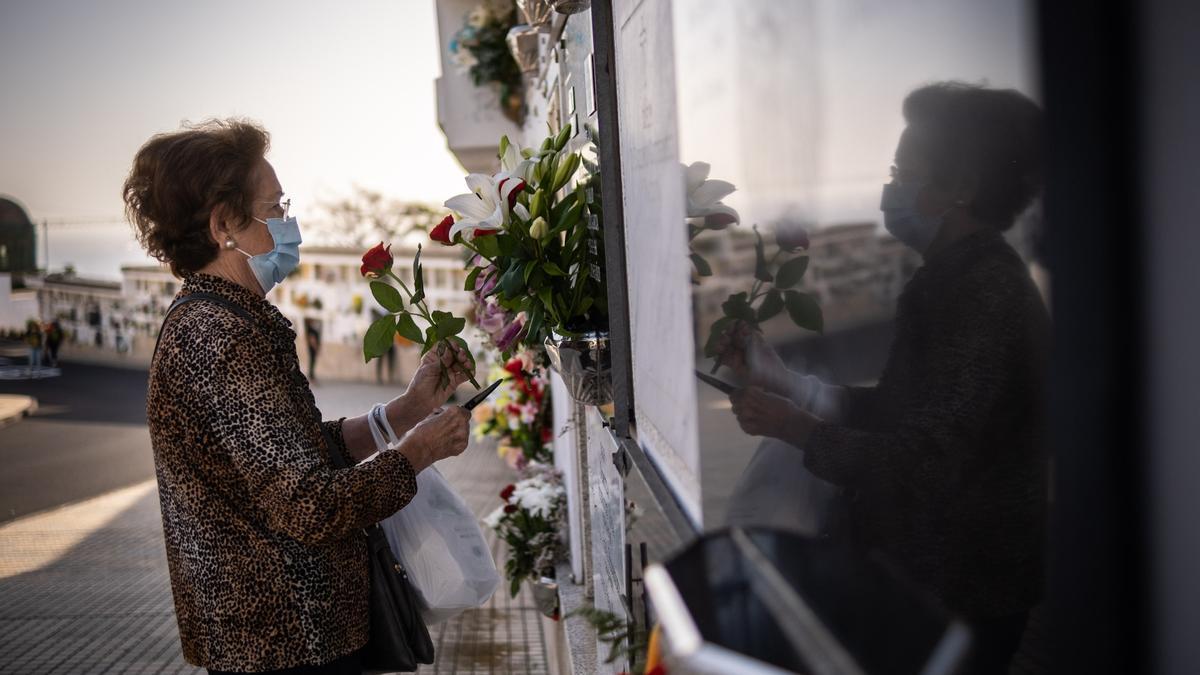 Una mujer coloca flores por el Día de Todos los Santos.