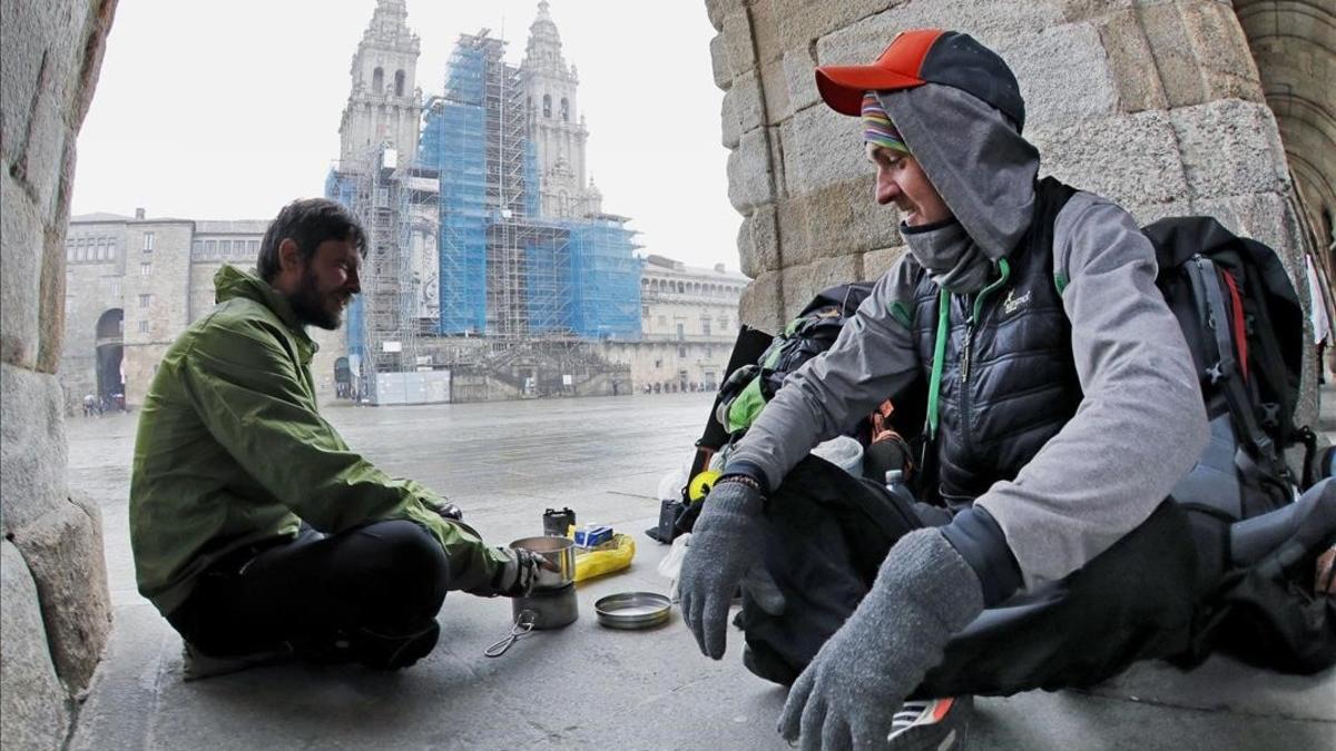 Dos peregrinos checos que llegaron desde Bordeaux se cobijan del frío con un hornillo debajo de los arcos del palacio de Raxoi, en la plaza de Obradoiro.