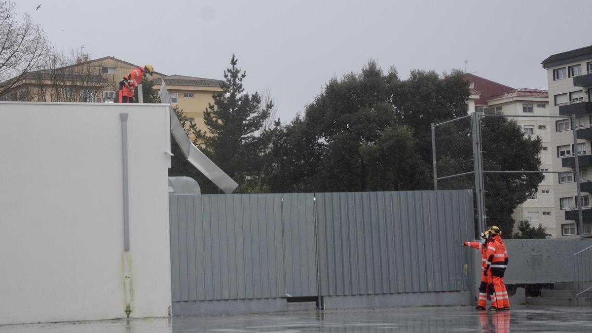 Los bomberos retiran unas chapas metálicas en la piscina de Campolongo