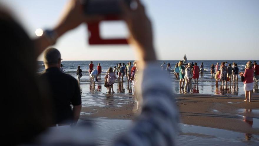 Una mujer maneja su móvil en una playa. // R. Solís