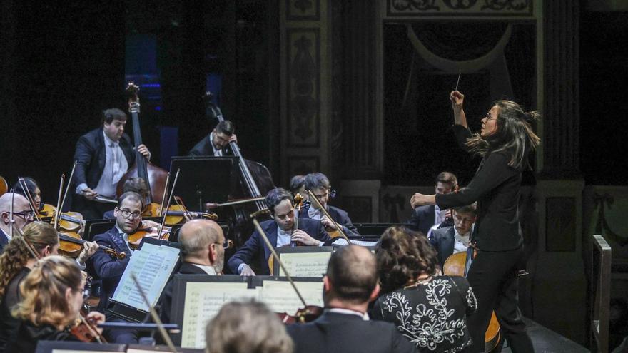 A la izquierda, Julia Cruz dirigiendo a Oviedo Filarmonía. Debajo, aspecto del teatro Campoamor, abarrotado.  | IRMA COLLÍN