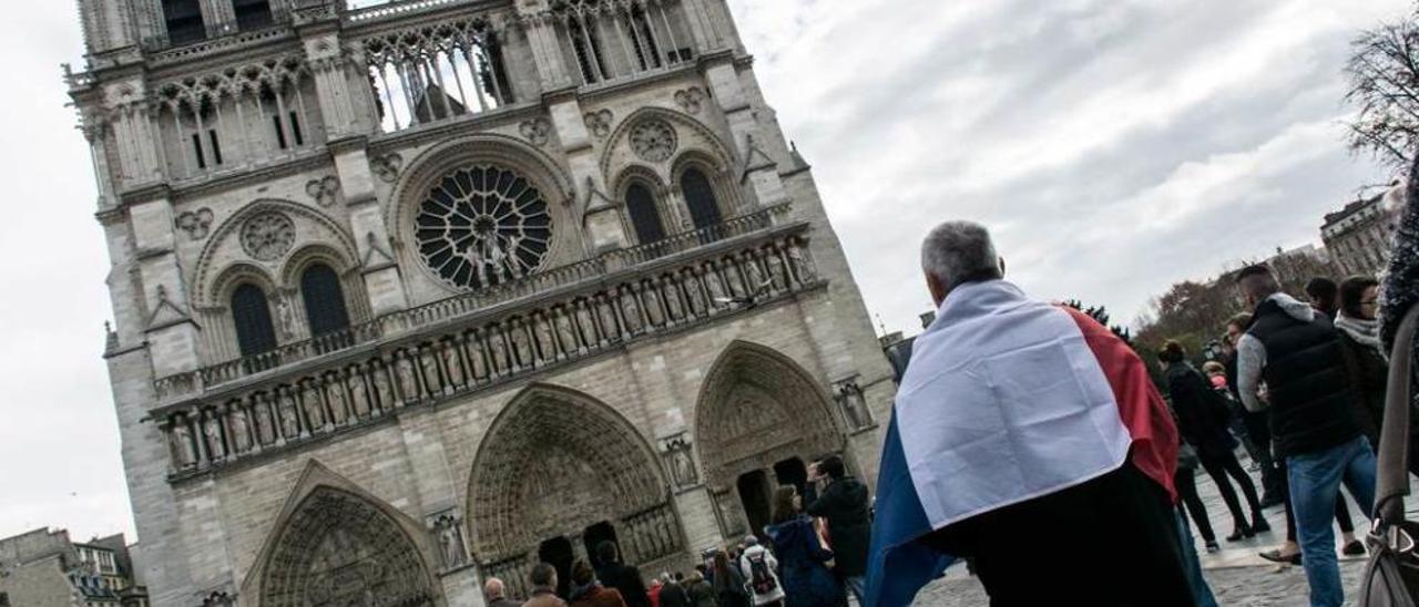 Un hombre con la bandera francesa en Notre Dame.