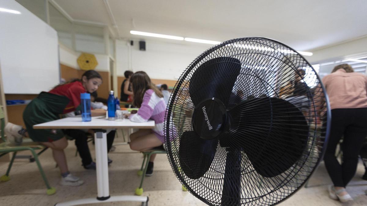 Unos alumnos combaten el calor en clase con un ventilador, en un centro de Barcelona.