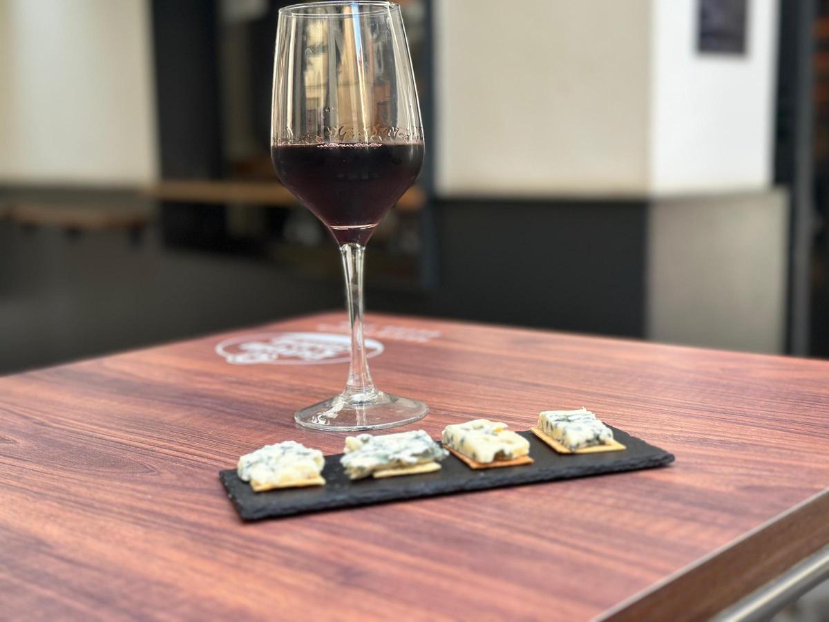 Una tabla de quesos gorgonzolla junto a una copa de Rioja.