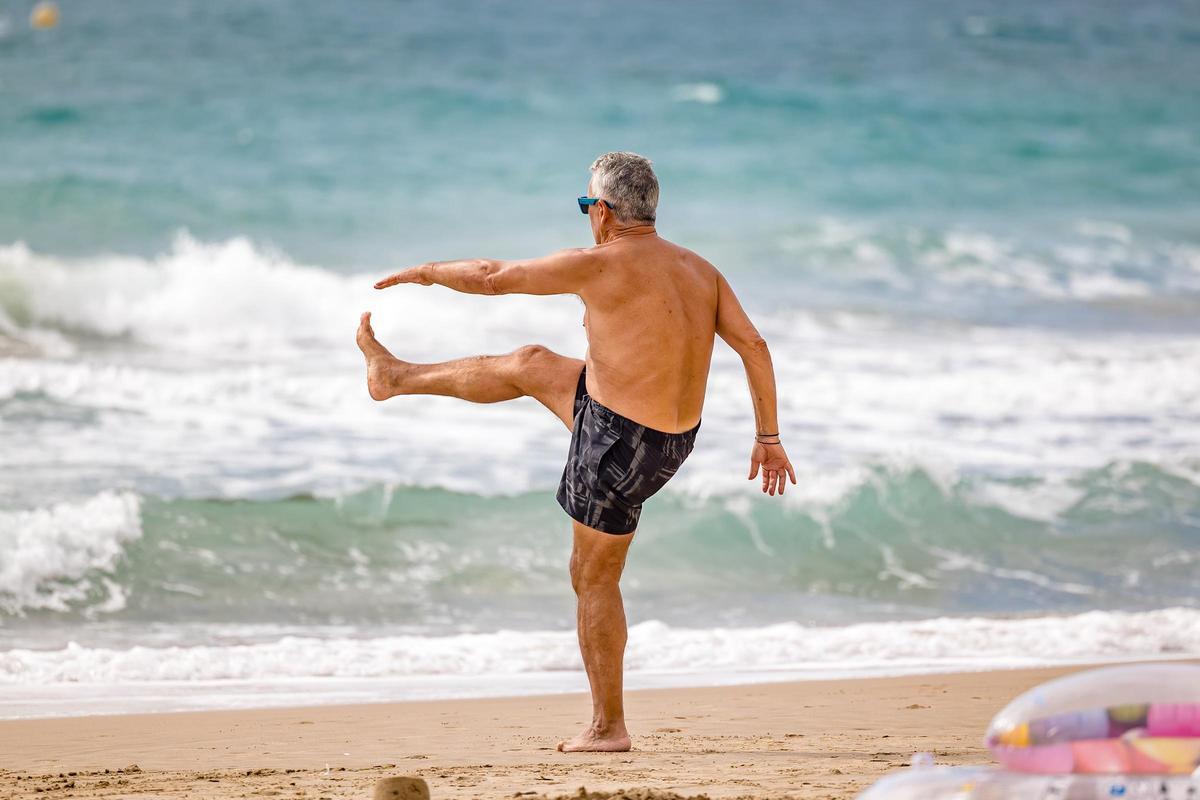 Un hombre practica deporte en la playa de Benidorm.