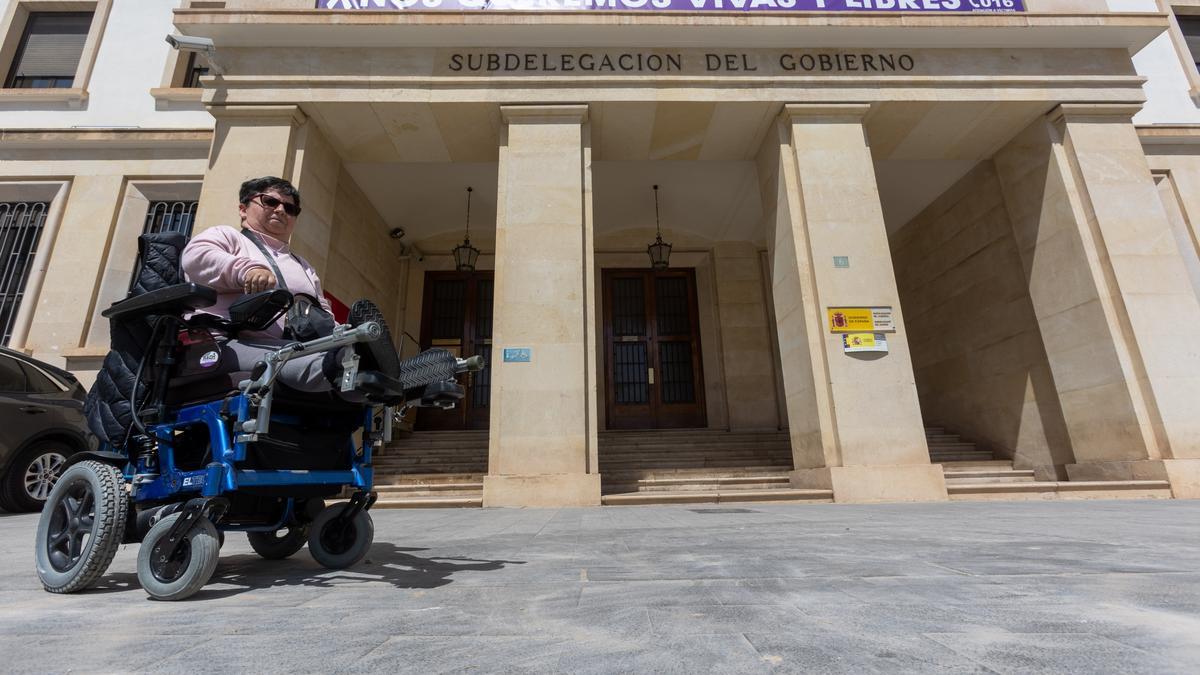 Una mujer en silla de ruedas, frente al edificio de la Subdelegación del Gobierno en Alicante