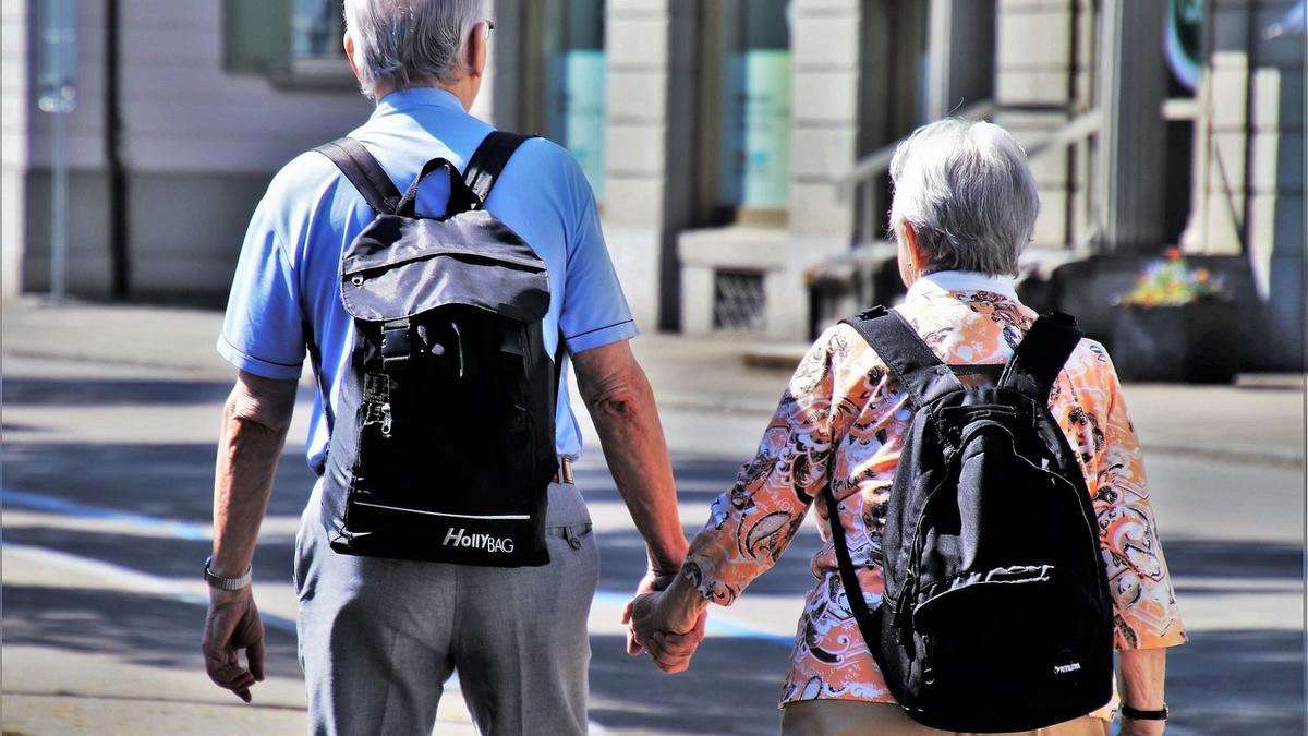 Dos jubilados pasean de la mano por la calle