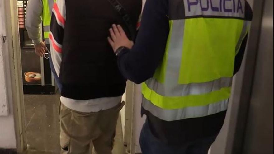 Un agente de la Policía Nacional lleva detenido a uno de los jóvenes grafiteros.