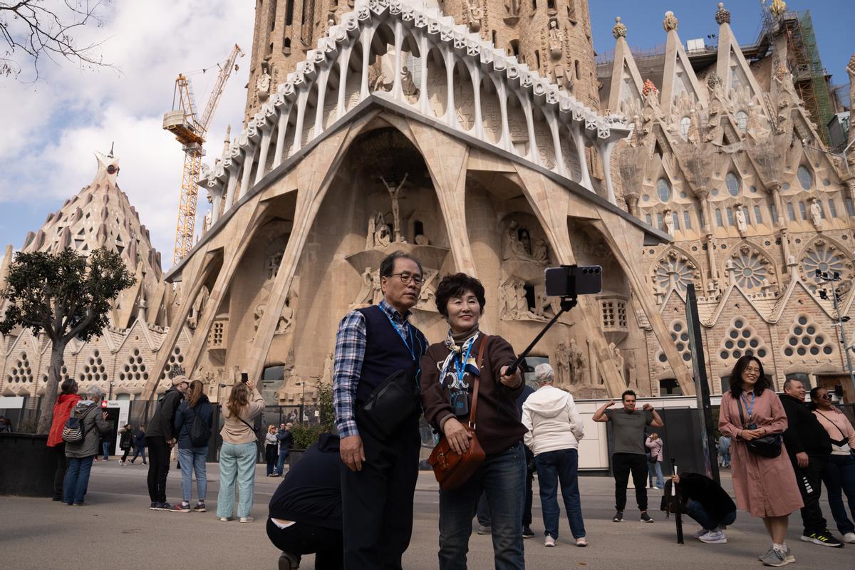 Archivo - Varios turistas se hacen fotos junto a la Sagrada Familia.