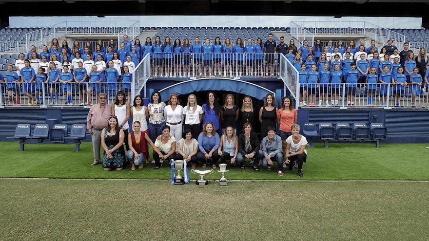 Foto de familia sobre el césped de La Rosaleda rodeadas del Málaga femenino.