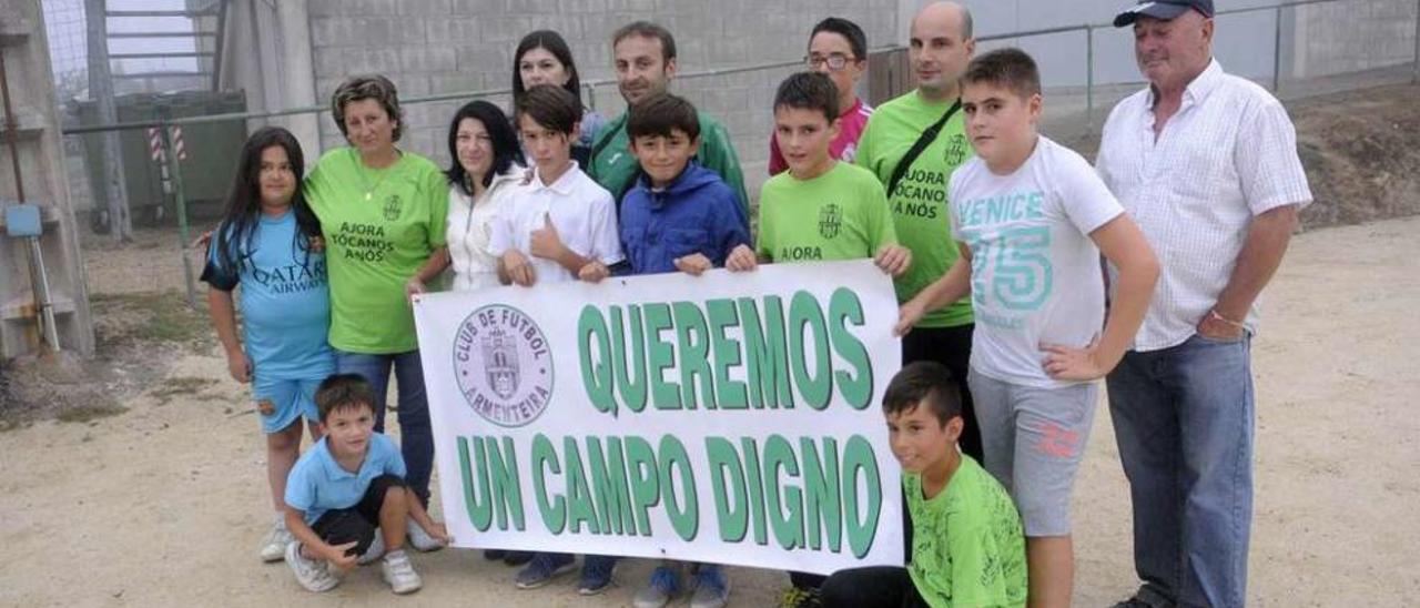 Directivos, padres y jugadores despliegan una pancarta reivindicativa en el campo de Armenteira. // Noé Parga