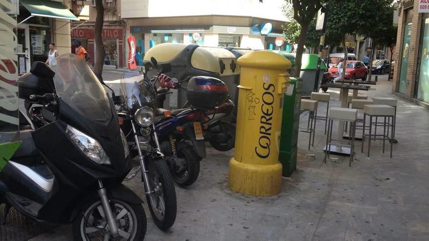 Las motos aparcan en la acera porque los contenedores ocupan la zona reservada para estos vehículos.