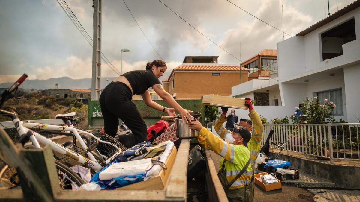 Bomberos y personal del Ayuntamiento ayudan a las familias a sacar enseres de sus casas antes de que llegue la lava del volcán.